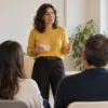 Una mujer practica una intervención ante un pequeño grupo de personas en una sala de formación.